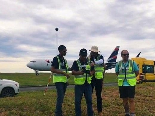 Equipe em pista, com aeronave comercial ao fundo