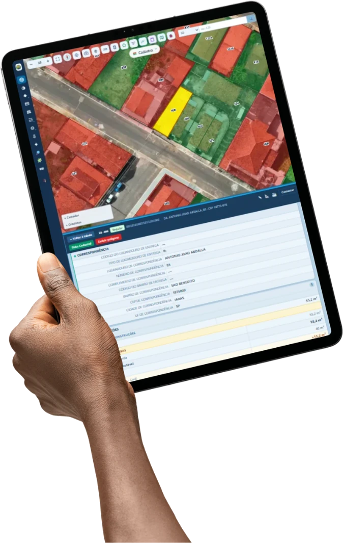 Tablet em campo com a ficha do imóvel aberta, mostrando a área cadastrada e a área aferida sobre a ortofoto